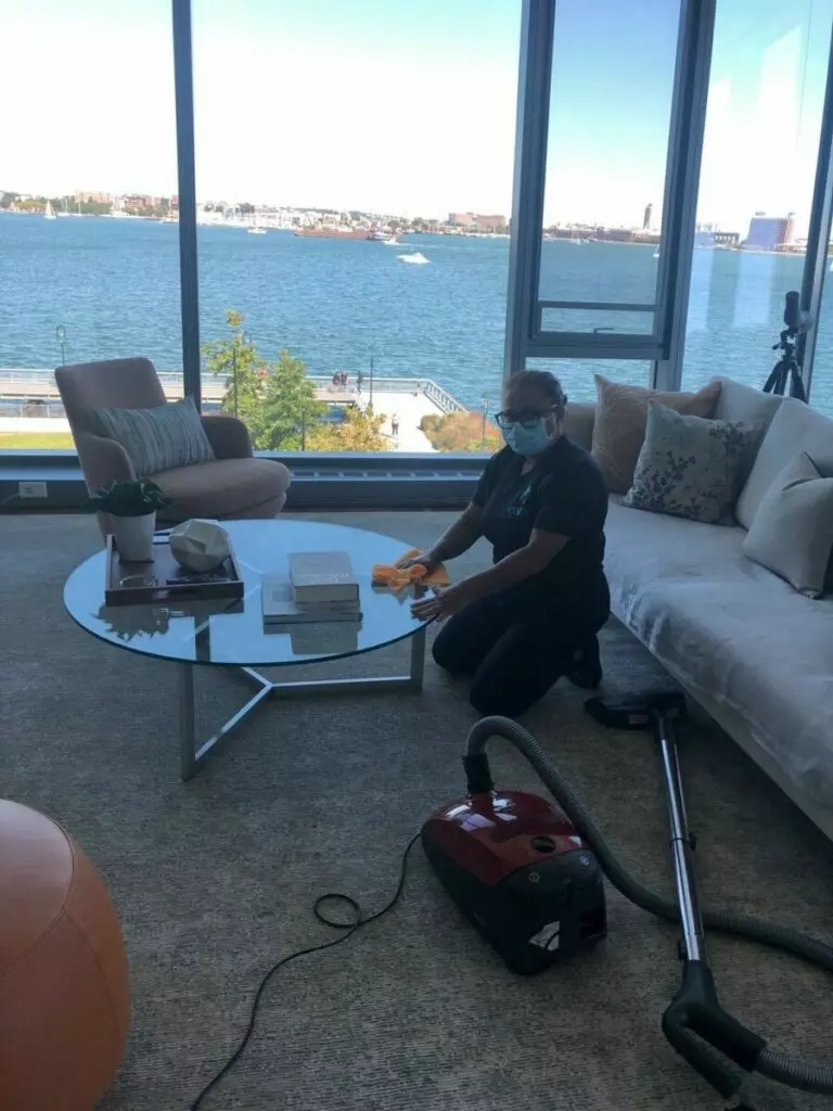 A woman cleaning a living room with a vacuum in Boston.