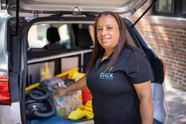 A woman in a black shirt standing in the trunk of a car, offering cleaning services in Boston.
