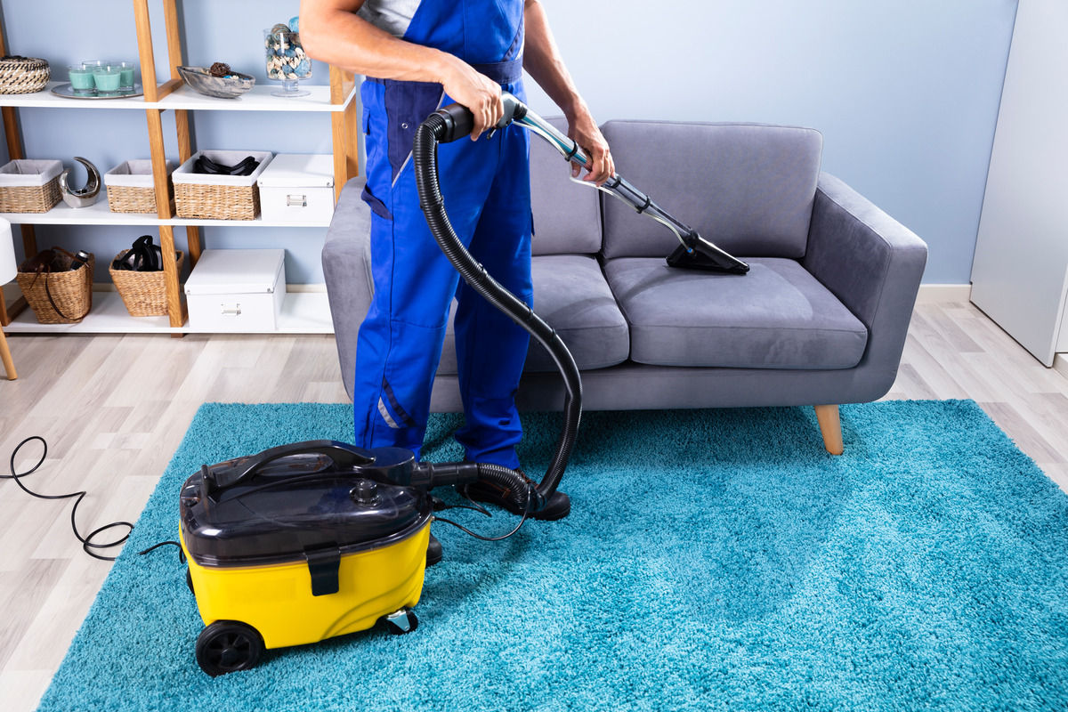 a man cleaning a sofa using a vacuum cleaner