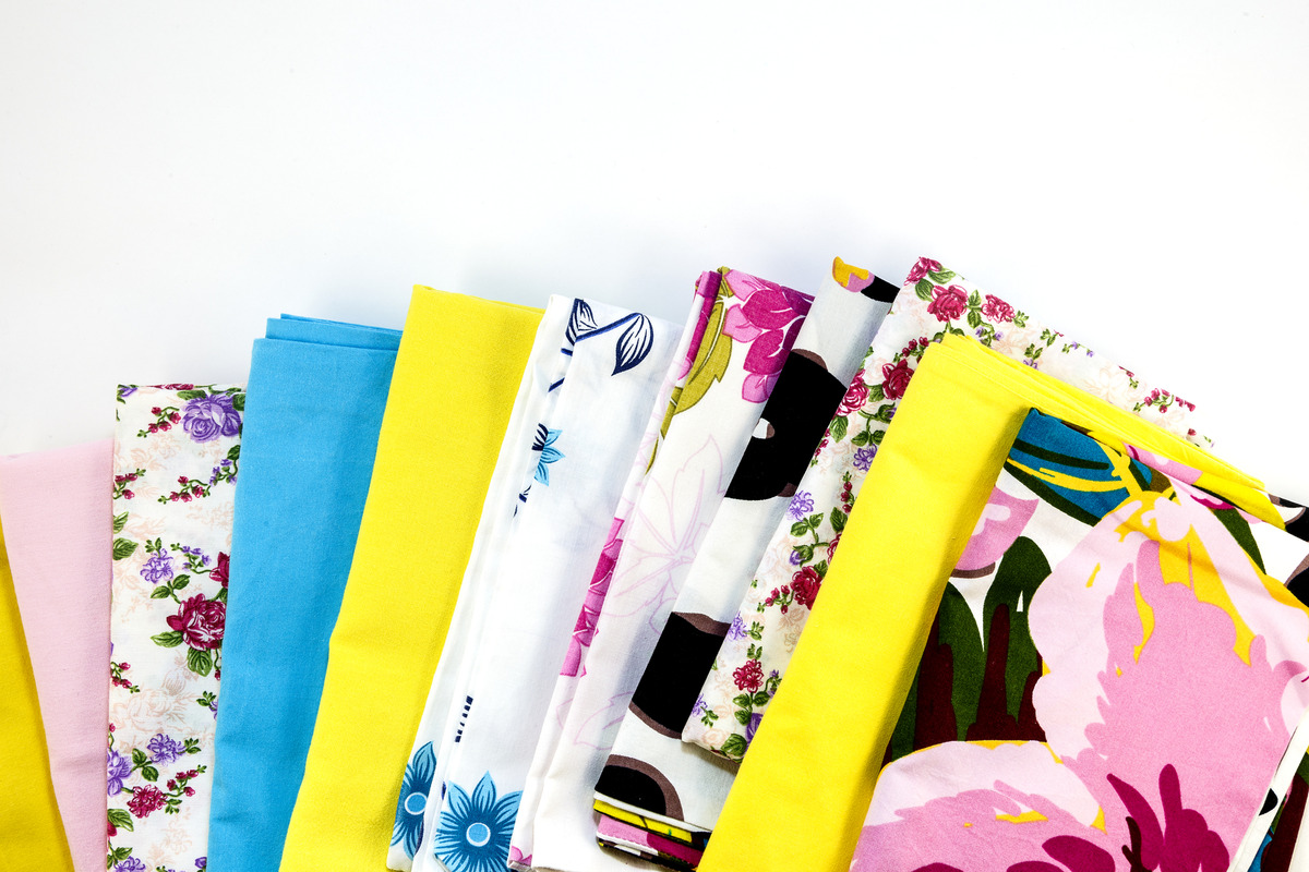 a stack of colorfull pillowcases ovetr a white background
