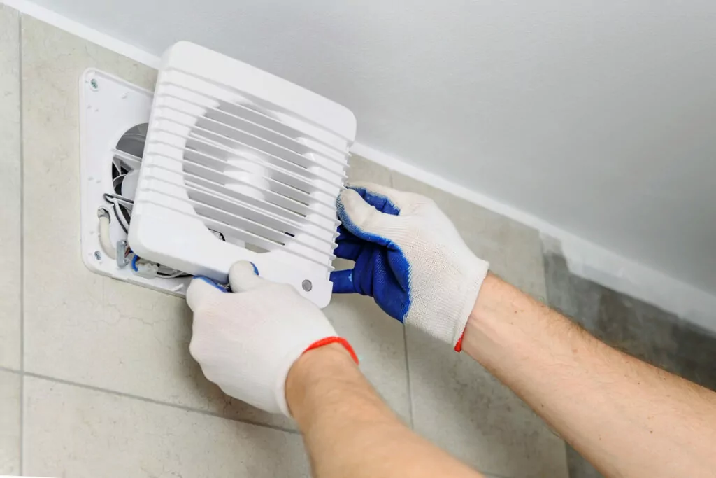 an image of a person's hands wearing gloves gently removing a cover of a wall mounted fan
