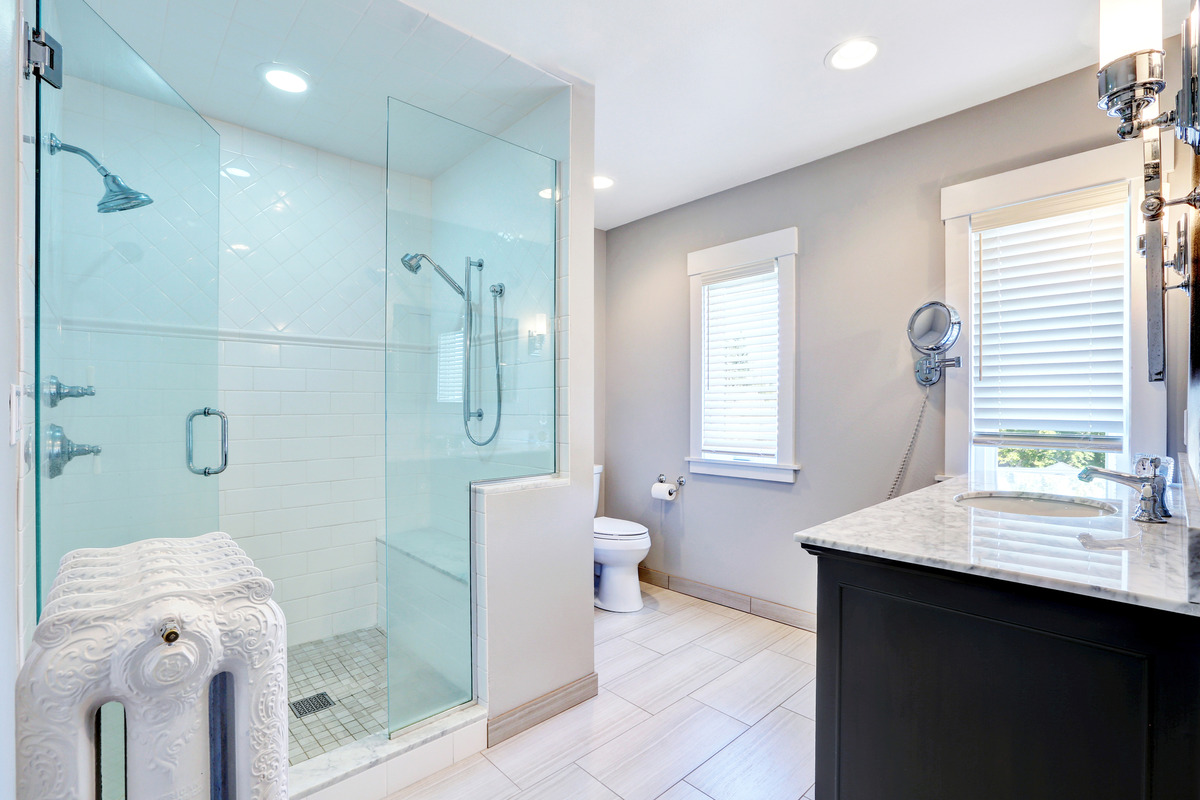 an image of a roomy bathroom featuring a light blue shower glass door