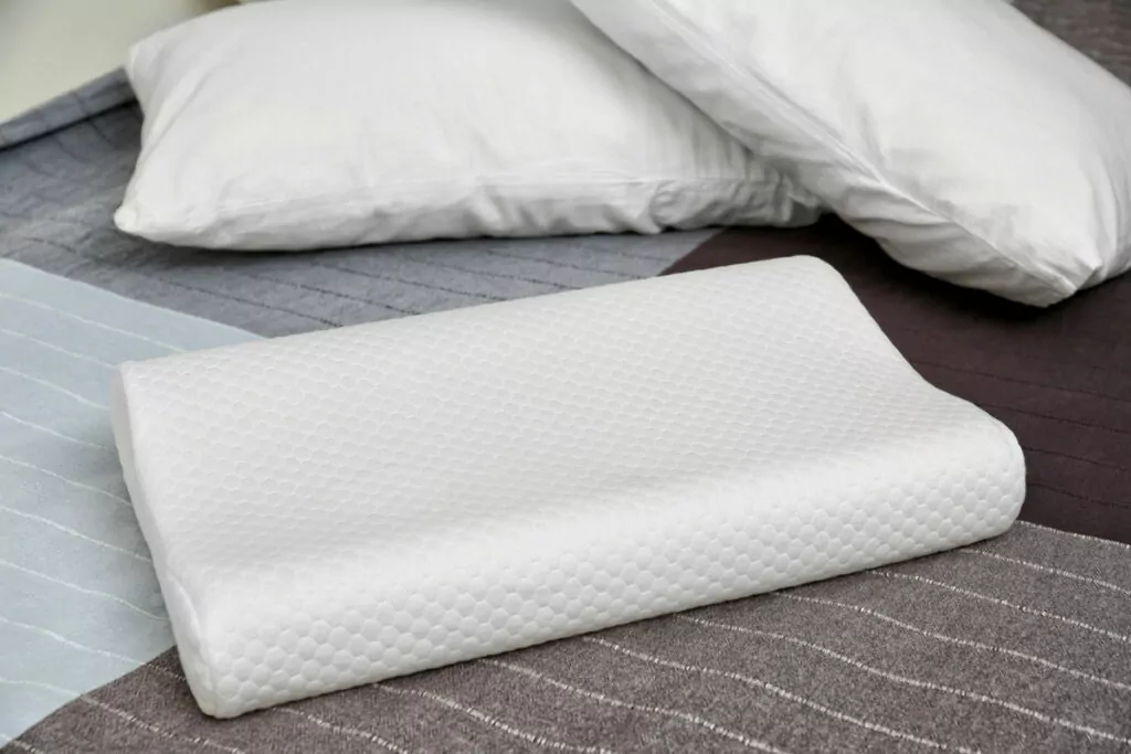 image of an orthopedic pillow placed on a bed, accompanied by smaller micro bed pillows