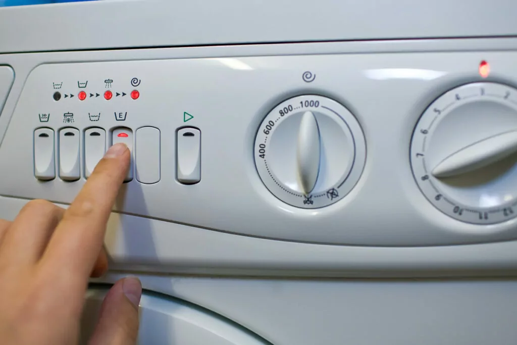 an image of a finger gently pressing the button on a washing machine's settings panel