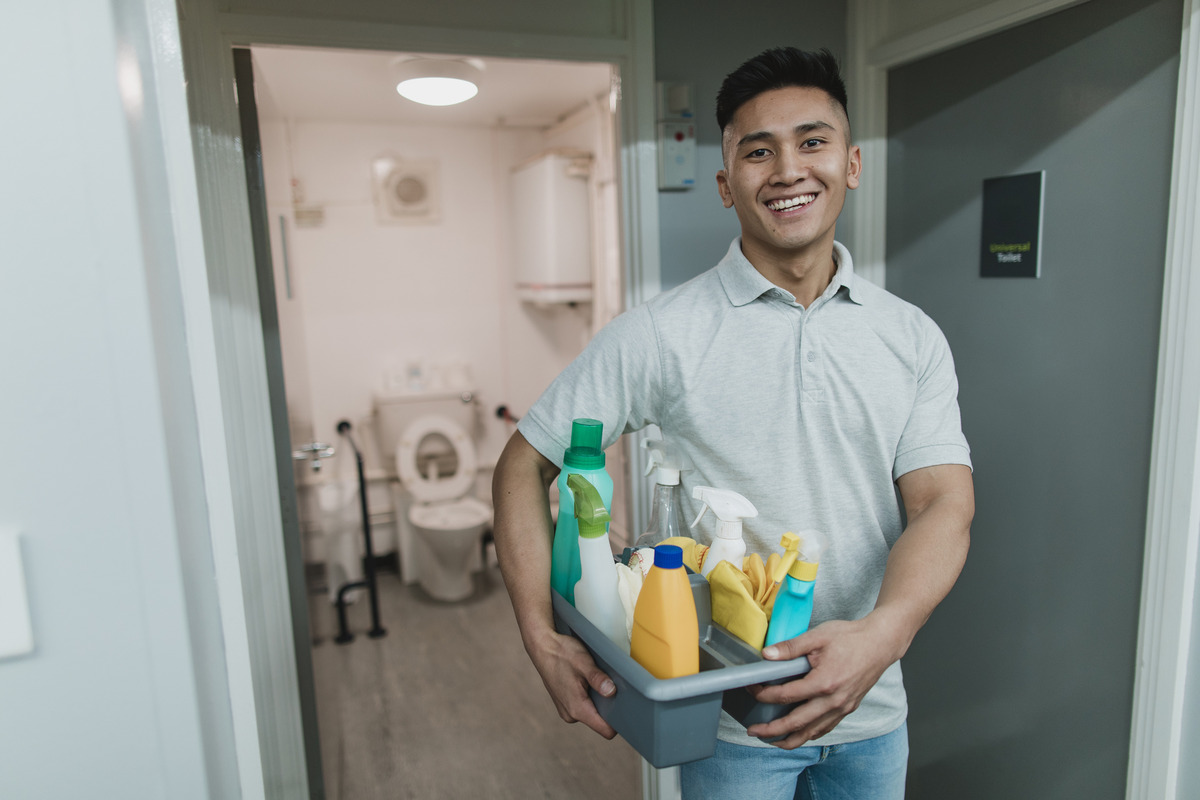 an image of a male cleaner holding a tray filled with cleaning products