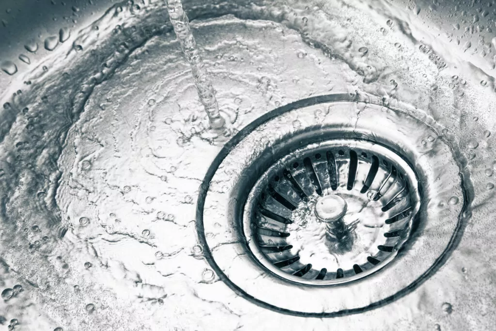 close-up view of a kitchen sink drain with water flowing from the faucet