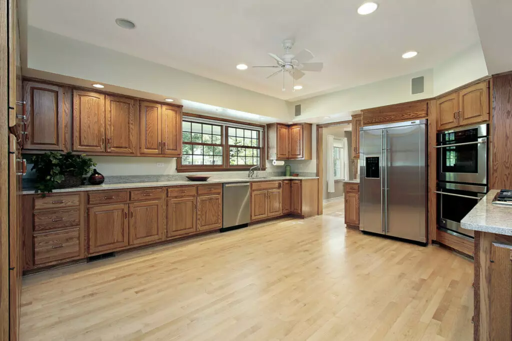 A kitchen with wood cabinets and stainless steel appliances, cleaned and maintained by a professional maid service in Boston.