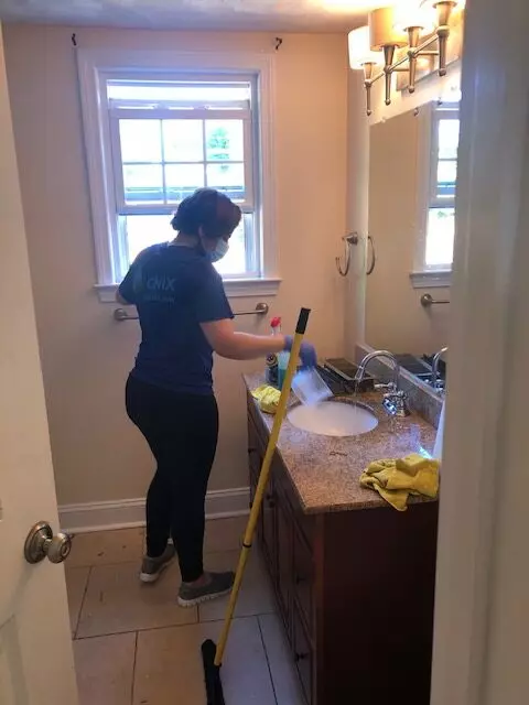an image of a woman, a professional Onix cleaner, preparing cleaning supplies for the removal of bathroom mold
