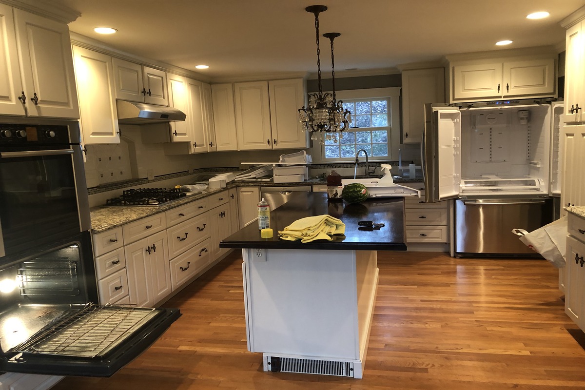 image of a well-organized kitchen with stainless steel appliances, an open refrigerator, and an oven