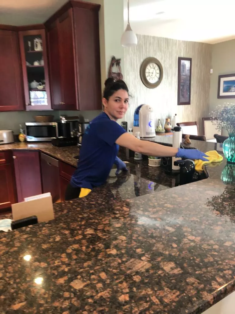 an image of a female onix cleaner wiping the granite kitchen countertop