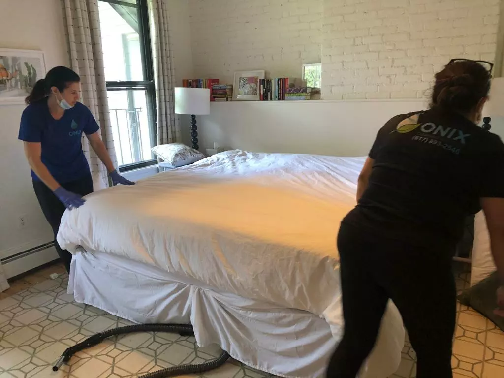 an image of two female onix cleaners adjusting the bed mattress