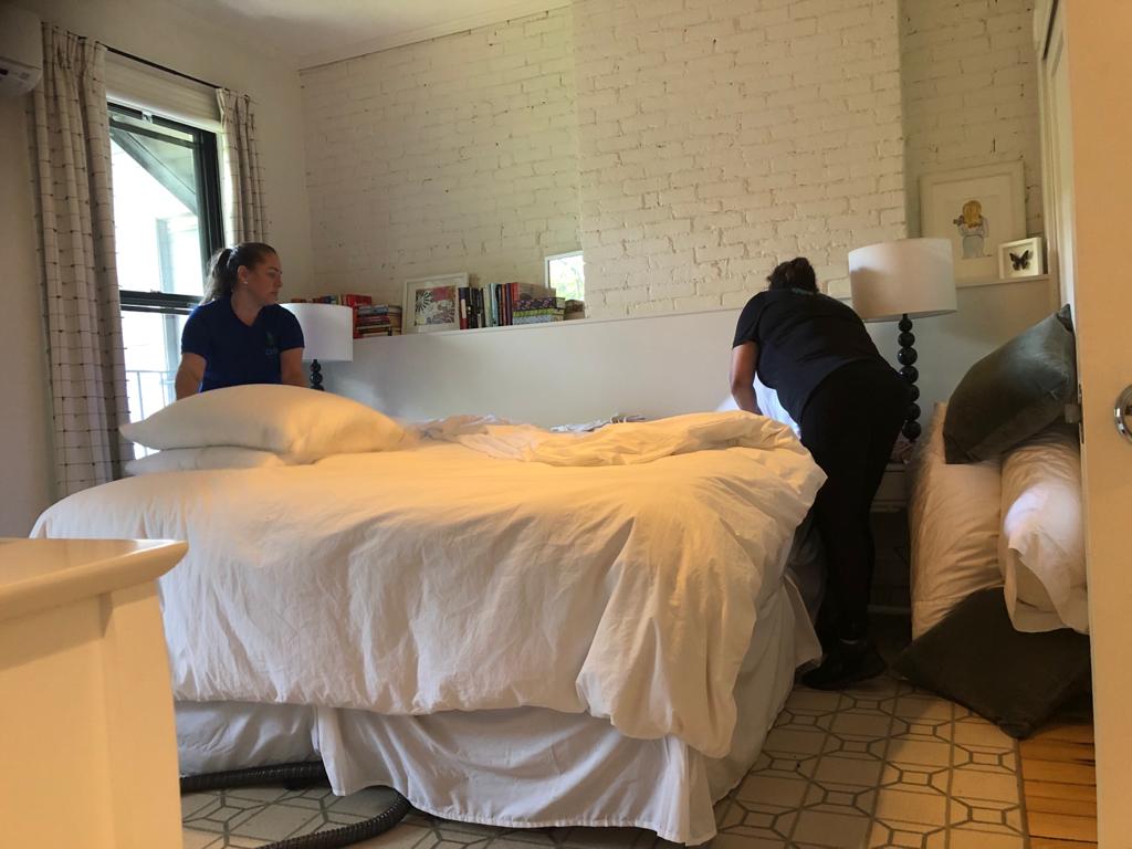 two female housekeepers assisting each other in adjusting a mattress