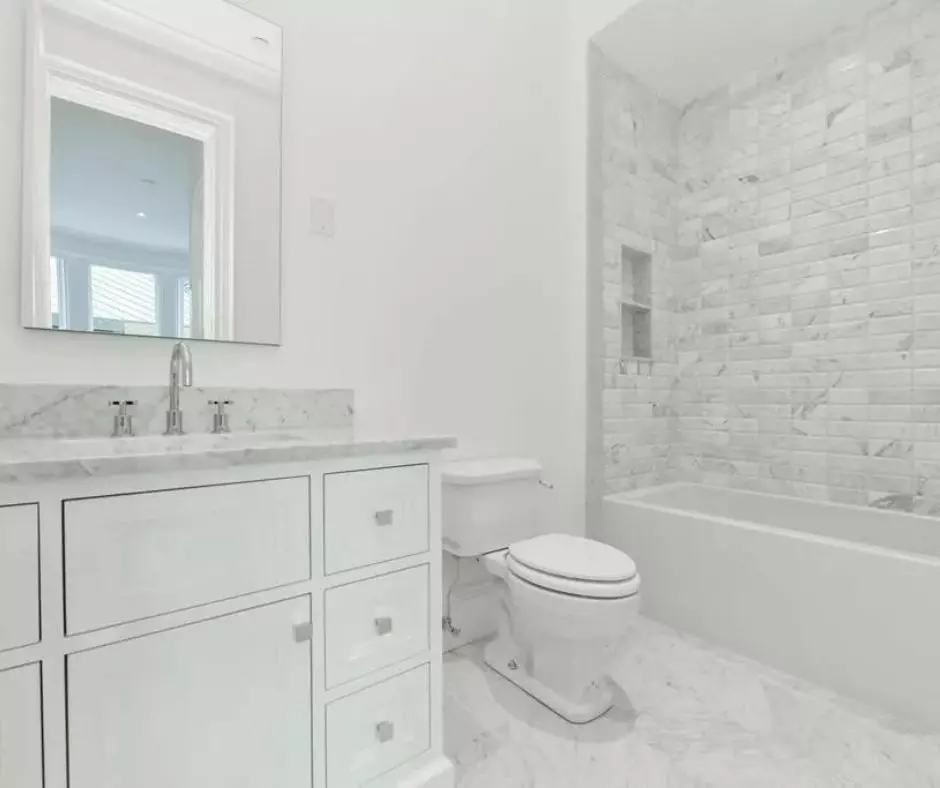 A pristine bathroom with elegant marble tile and a toilet.