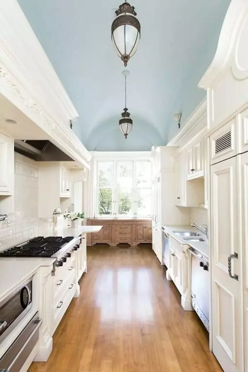 An Airbnb kitchen with a white color scheme, blue ceilings, and warm wood floors.