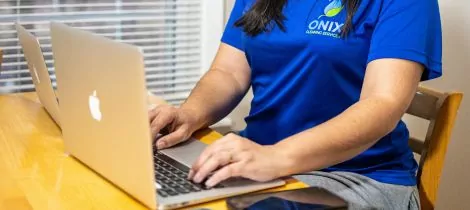 A woman in a blue shirt using a laptop.