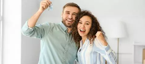 Happy couple holding keys to their new home.