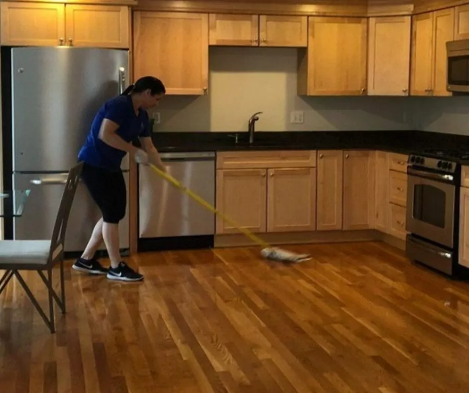 A woman providing Airbnb cleaning services by mopping the floor.