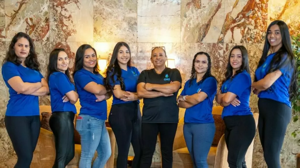 A group of women in blue shirts standing in a lobby, wearing templates.