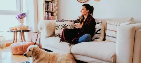 A woman sitting on a couch with her dog.