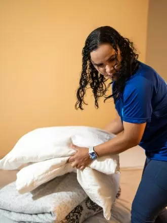A woman, move in, putting pillows on a bed.