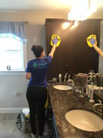 A woman cleaning a bathroom with a mop after a move out.