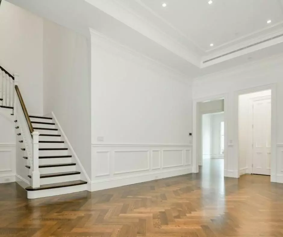 An empty room with hardwood floors, ideal for move in or move out. A staircase adds a touch of elegance to the space.