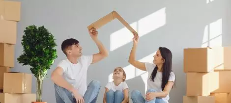 A family sitting on the floor in front of moving boxes.