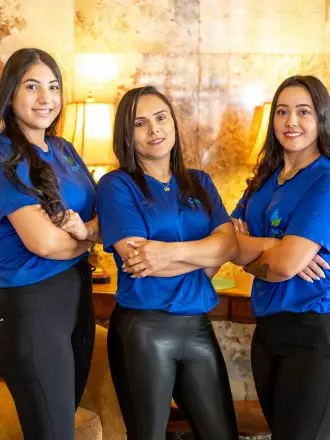 Four women in blue shirts standing in front of a couch ready to move out.