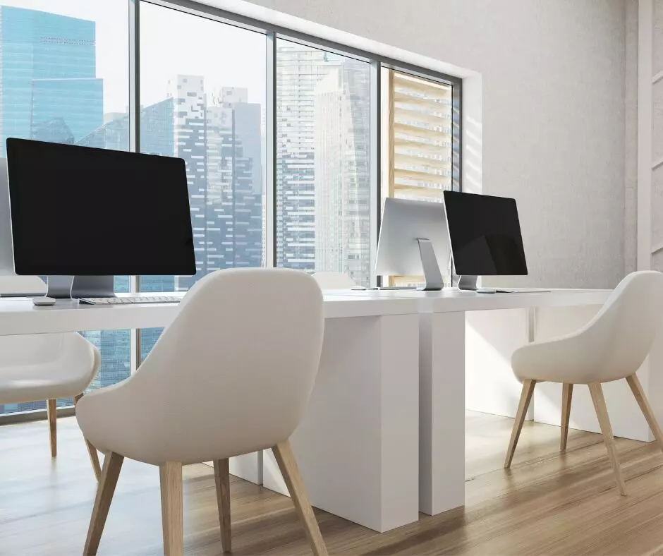 A white office featuring two monitors and two chairs, perfect for office cleaning or creating professional templates.