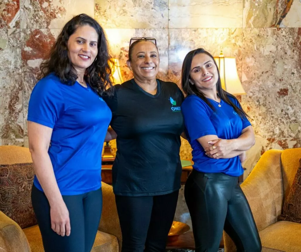 Three women in blue shirts posing for a photo.