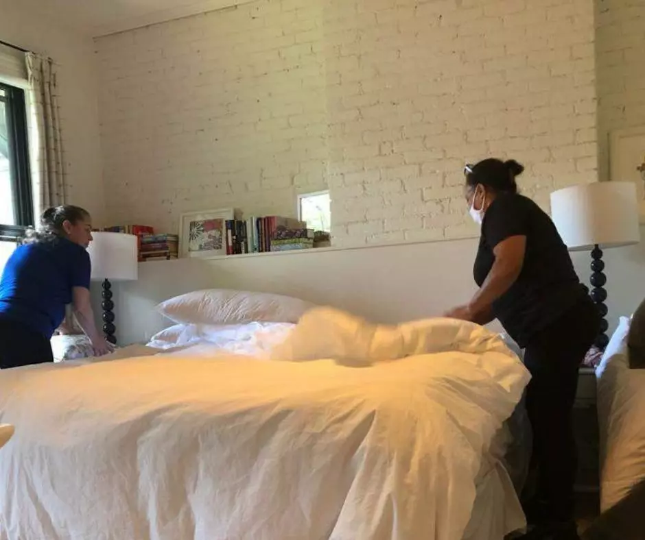 Two women working on recurring cleaning templates on a bed in a room.