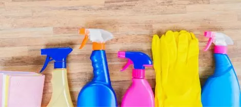 A variety of standard cleaning supplies on a wooden surface.