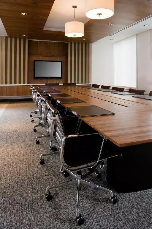 A modern boardroom with a long table, black chairs, a presentation screen, and commercial cleaning service templates accessible for maintenance.