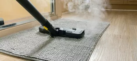 A steam mop is being used in conjunction with sanitization templates to clean a rug.