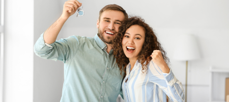 A cheerful couple holding keys and celebrating possibly a new home ownership, ready to use their living room cleaning templates.