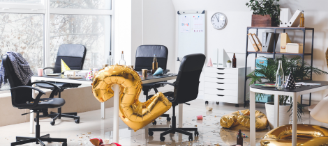 An untidy office space with scattered party decorations and a deflated number six balloon, in need of a special event cleaning.