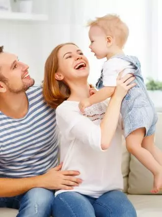 A happy family moment with a mother holding a toddler while sitting next to a smiling father in their freshly cleaned kitchen.